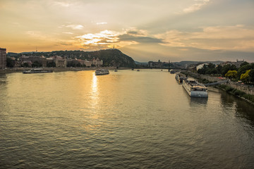 Budapest waterfront urban city scape in sunset time with Danube river ships and sun glares