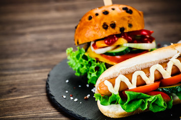 Tasty burger and hot dog on black stone