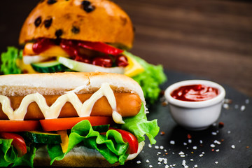 Tasty burger and hot dog on black stone