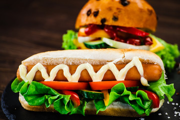 Tasty burger and hot dog on black stone