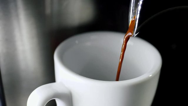 Pouring coffee into cup from electric coffee machine shooting in 4k resolution in slow motion