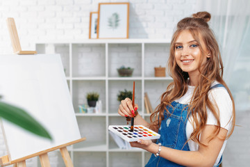 Pretty talented female painter painting on easel