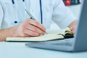 Male doctor or medical student holding ballpoint pen and writing on notepad. Therapist fills the...