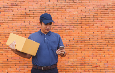 Asia delivery man are holding a cardboard box delivery to his customer.Delivery man are checking customer from the mobile.