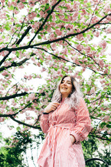 Beautiful Young Woman Enjoying Sunny Day in Park during Cherry Blossom Season