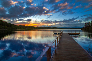 Boat dock. Sunset over the lake. Wooden pier on the lake. Pier on the background of sunset.