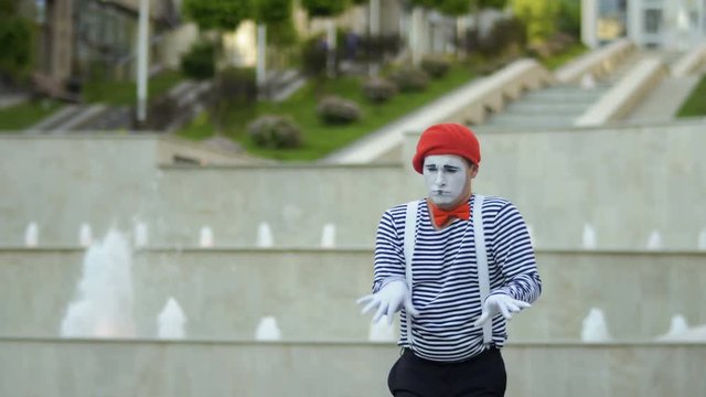 Funny mime in red beret playing piano at fountain background