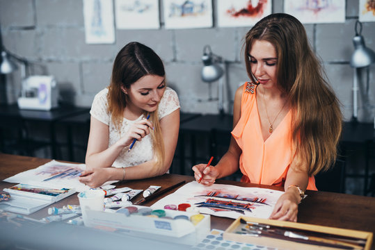 Two adult female students working on their paintings studying at art school