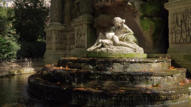 Medici Fountain with sculpture of Acis and Galatea and autumn leaves in water. Visiting Luxembourg Gardens in Paris, France