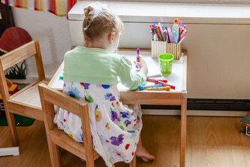 Cute little girl painting in her room at home