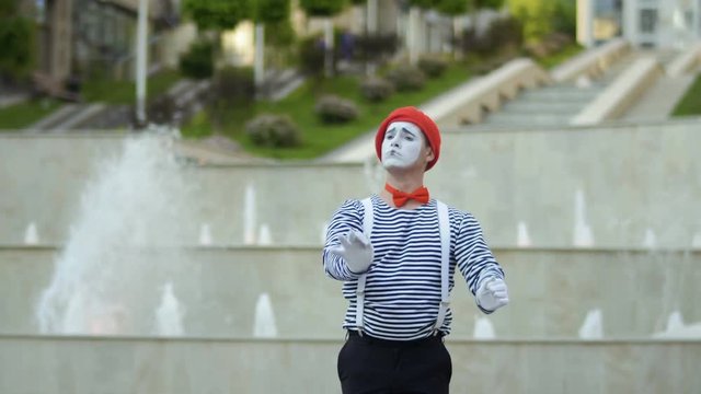 Mime conductor gesticulating hands at fountain background