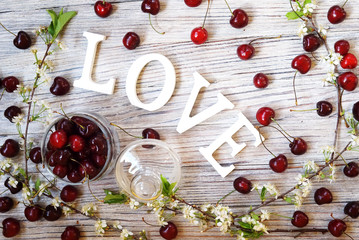 red and Burgundy cherry with flowering branches on a white textured background with water drops