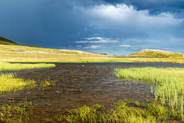 Fototapeta premium Lake in the wilderness with dark thunder cloud at the sky