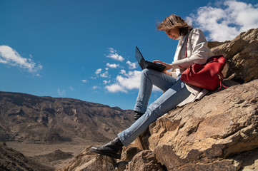 girl working on a laptop in the mountains