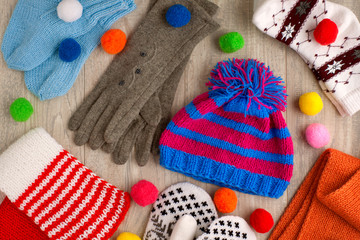 Obraz na płótnie Canvas Warm clothes on a wooden background. View from above. Hat, gloves, mittens, socks and scarves for the autumn and winter seasons.