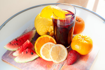 Glass of sangria wine on a natural background surrounded by fresh fruit, citrus, strawberry, watermelon.