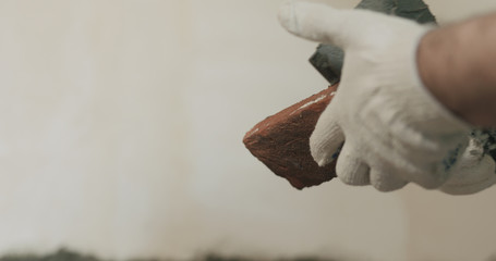 closeup worker applying concrete glue to brick tile