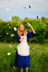 Beautiful young woman dressed in costume throwing playing cards into the air
