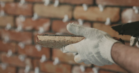 closeup worker applying concrete glue to brick tile
