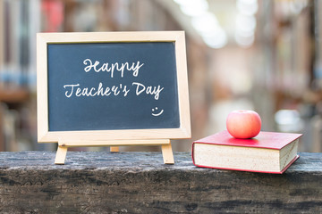 Happy teacher's day greeting announcement on black chalkboard on blur school college library background for Education concept