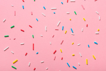 colorful sprinkles over pink background, decoration for cake and bakery