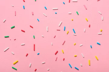 Foto op Plexiglas colorful sprinkles over pink background, decoration for cake and bakery © Alisa