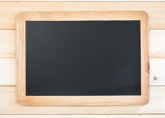 Blank black chalkboard frame with copyspace hanging on pine wood wall for announcement and restaurant menu
