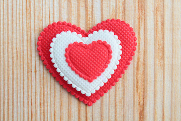A beautiful red soft heart made of cloth on a light new board. Close-up. Background. Texture.