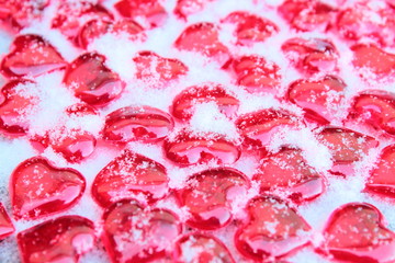 Beautiful little red decorative hearts on white snow. Close-up. Background. Texture.