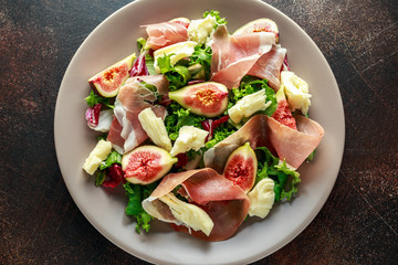Fresh figs salad with prosciutto, green mix and cheese in a plate
