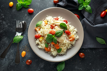 Steamed cod fish with rice and cherry mix tomatoes and basil herbs in a plate