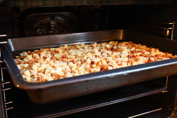 Rusks. Finely diced dried bread on a tray in the oven.
