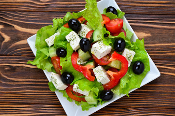 Greek salad on a wooden background. Space for text or design.