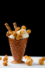 Ice cream with caramel and popcorn on a  black background. Space for text or design.