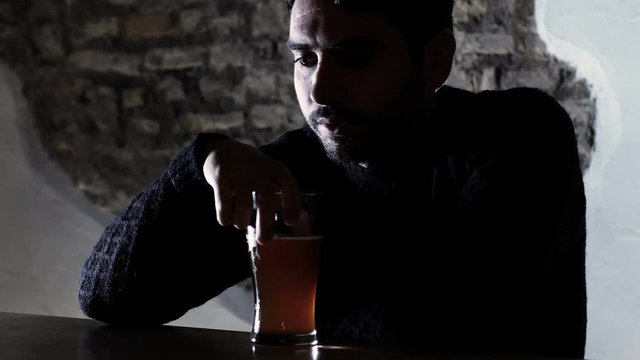 Sad young man lonely in pub drinking beer. alcoholism, loneliness, despair