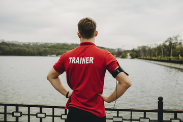 Fototapeta premium Man in trainer shirt standing on embankment