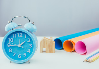Alarm clock ,pencil and color paper on table.