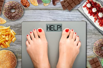 Poster Junk food or sugar sweets temptations when you diet concept with woman feet on weight scale   © adrian_ilie825