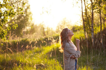 Cute charming girl in summer in the field. Young woman is happy and feels free outdoors