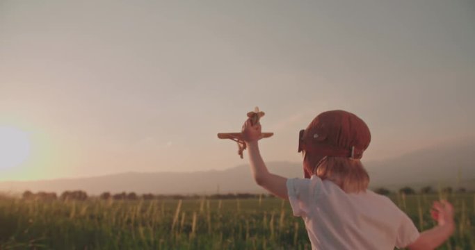 emotional shot happy boy with toy airplane in wheat field is running. dream, childhood, memories concept.Slow motion, sunset time.