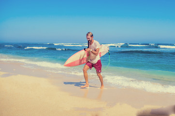 Fototapeta na wymiar Happy surfer holding leash in his teeth