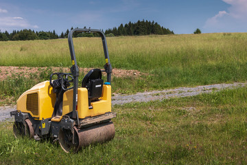 Obraz premium Alte gelbe Dampfwalze auf der Baustelle in der öffentlichen Natur