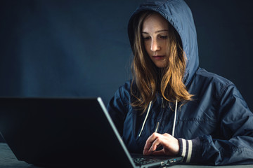 Girl hacker uses a laptop to hack the system. Stealing personal data and infection of malicious virus. © Artem