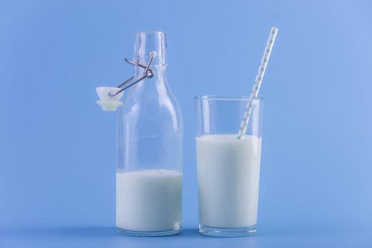 Bottle of fresh milk and a glass with a straw on a blue background. Concept of healthy dairy products with calcium