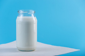 Glass bottle with fresh milk on blue background. Colorful minimalism. Healthy dairy products with calcium
