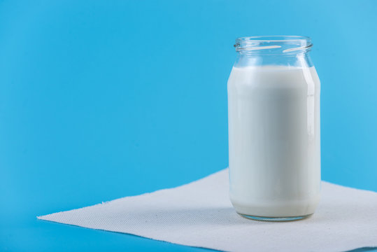 Glass bottle with fresh milk on blue background. Colorful minimalism. Healthy dairy products with calcium
