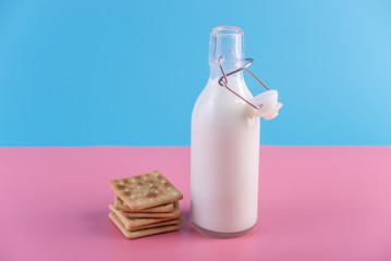 Glass bottle of fresh milk and cookies on pastel background. Concept of healthy dairy products with calcium