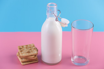 Glass bottle of fresh milk and cookies on pastel background. Concept of healthy dairy products with calcium
