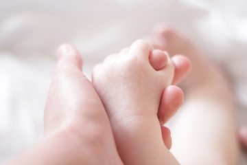 the child's hand holds the finger of an adult