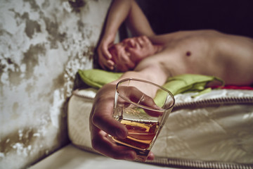 Fototapeta na wymiar Husband's dependence on alcohol. Lace-up. A glass of whiskey. Naked man Pastel colors